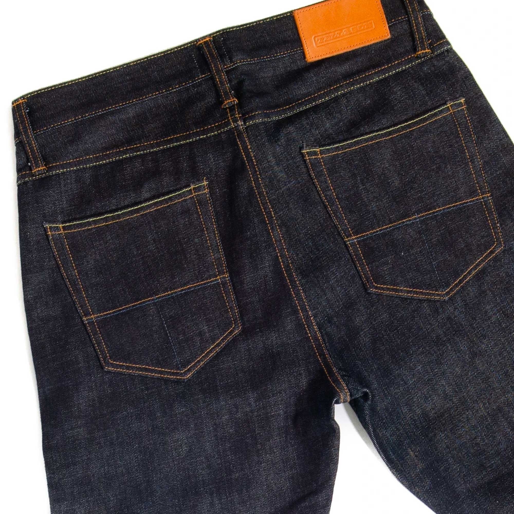 Rear view of dark wash selvedge denim jeans with prominent back pockets and leather patch.