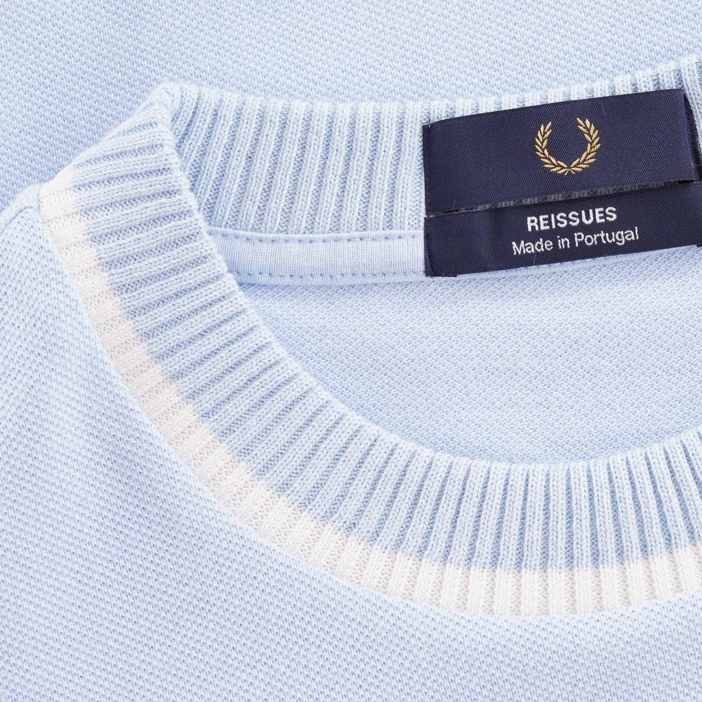 Close-up of the Fred Perry Reissues Made in Portugal label on the light blue t-shirt.