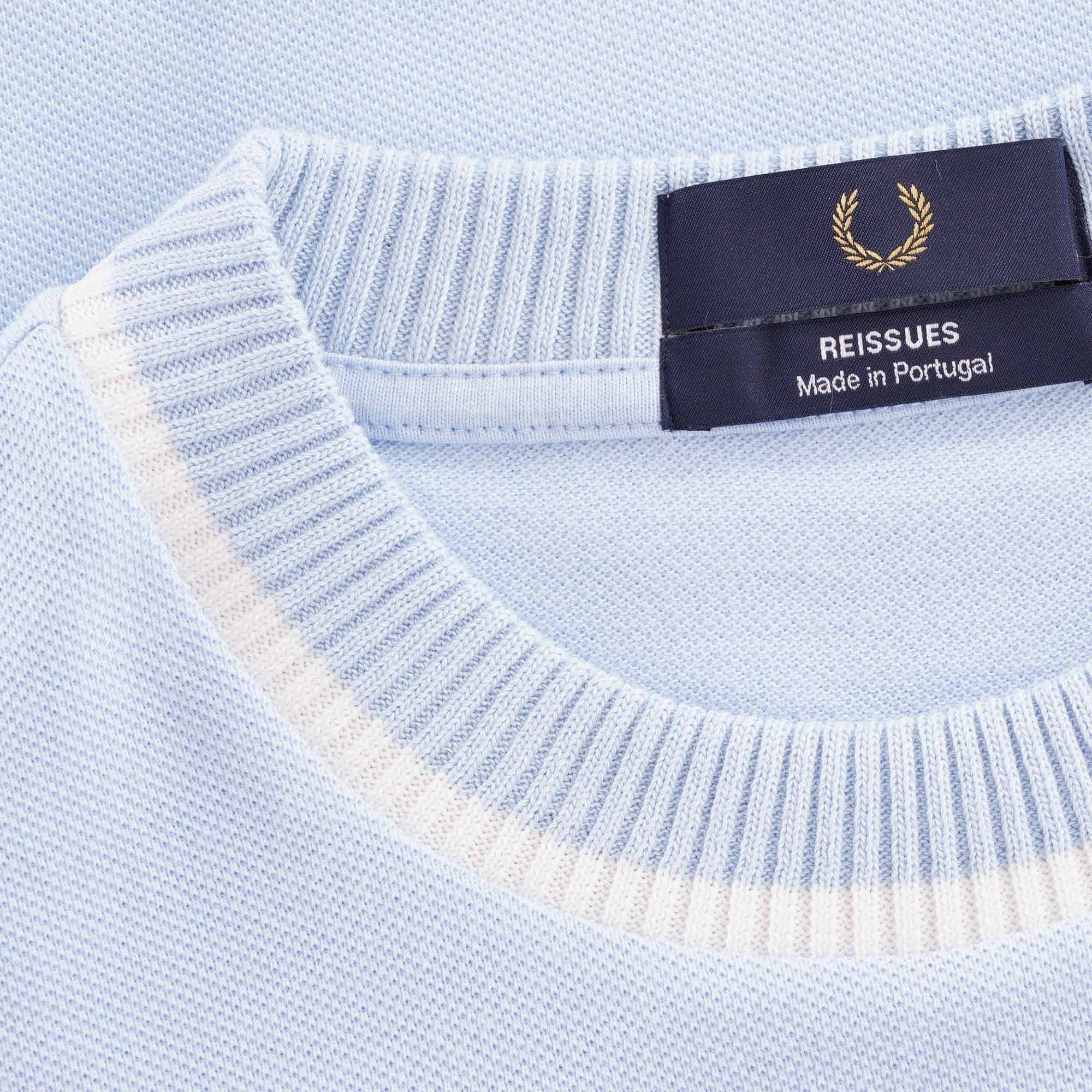 Close-up of the Fred Perry Reissues Made in Portugal label on the light blue t-shirt.