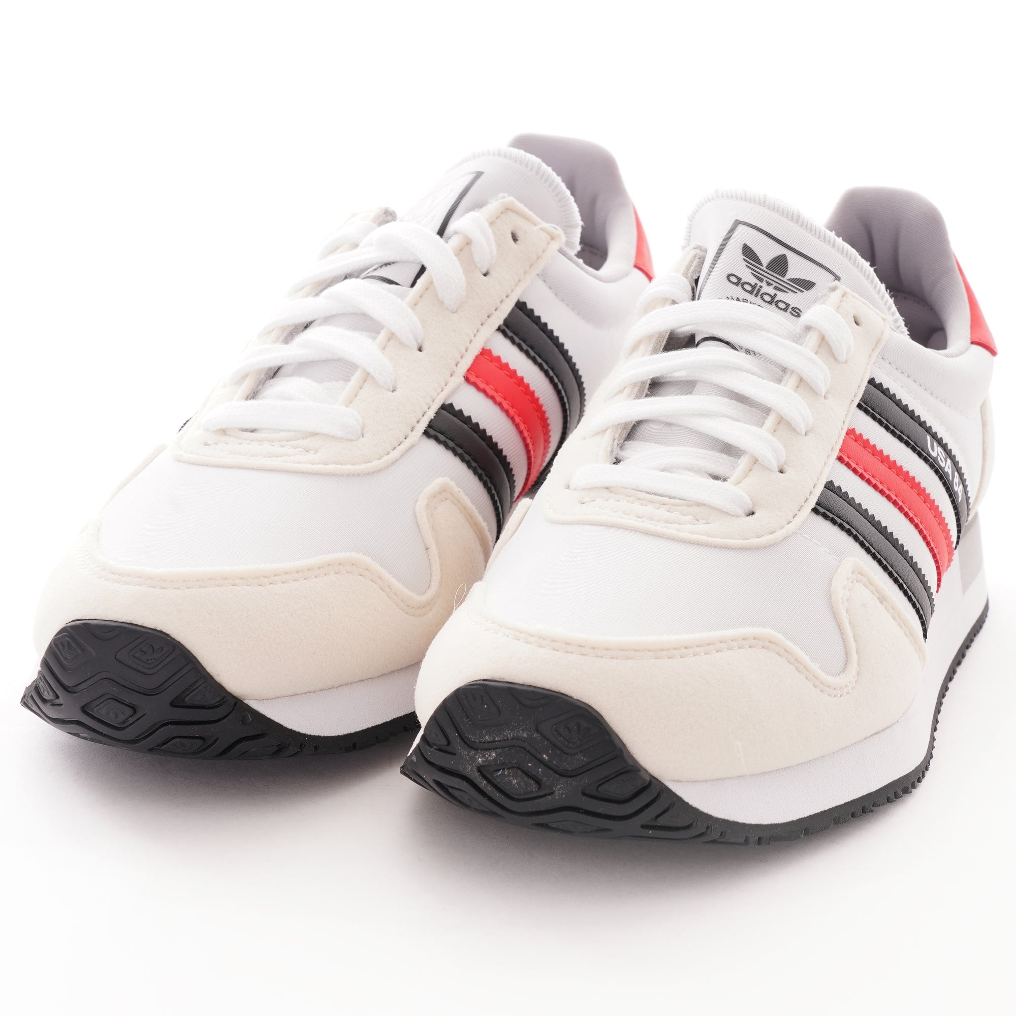 A pair of white, red, and black Adidas USA 84 trainers are shown from the front.