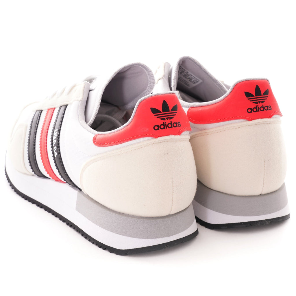 The rear view of a pair of white, red, and black Adidas USA 84 trainers.