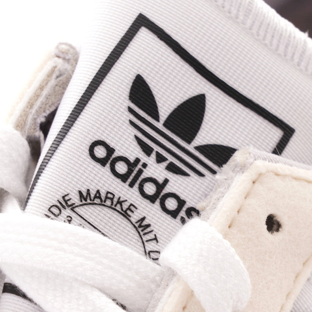 A close-up of the Adidas logo on the tongue of a trainer.
