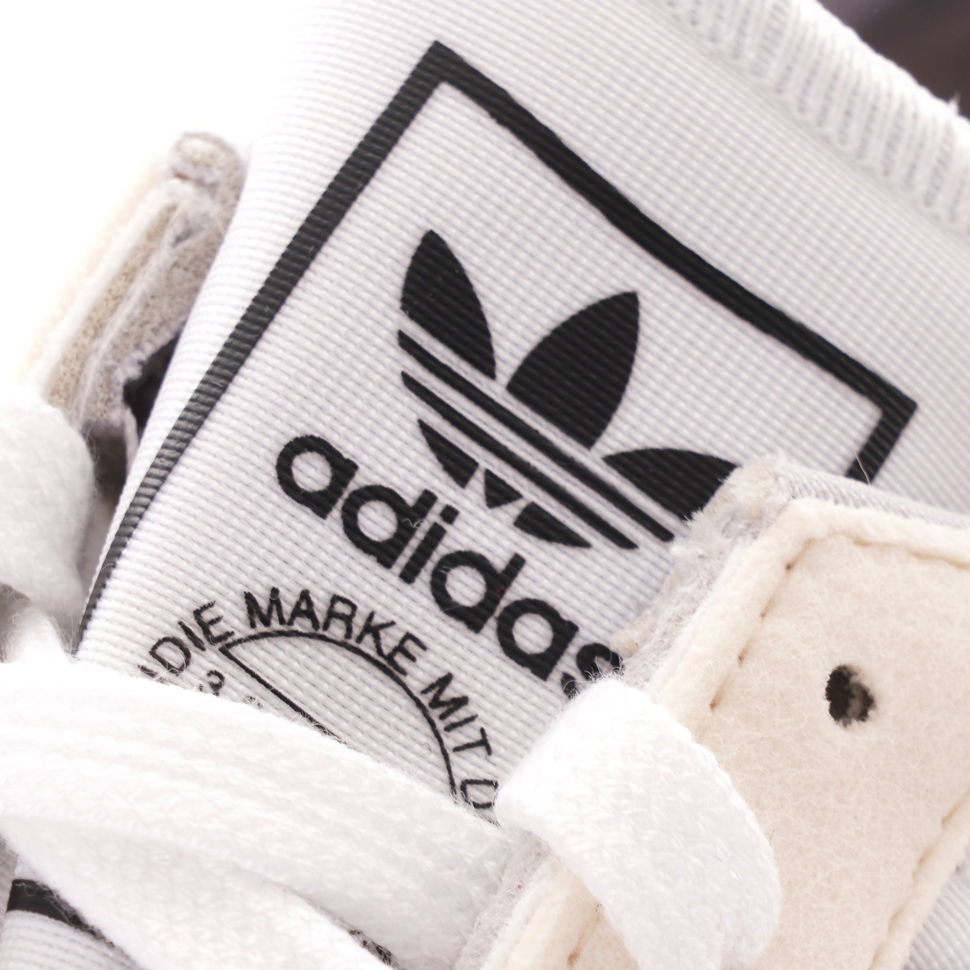 A close-up of the Adidas logo on the tongue of a trainer.