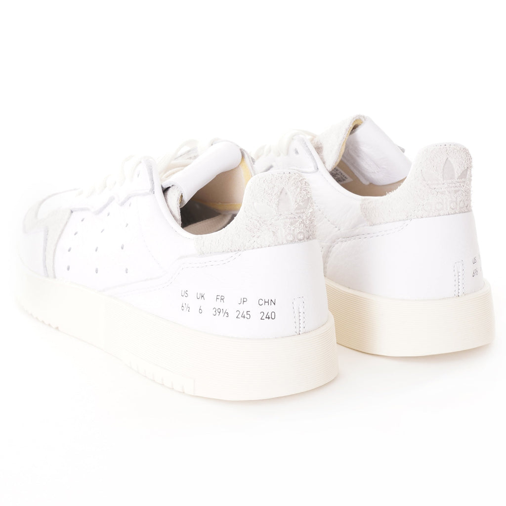 A pair of white adidas Supercourt sneakers, showing the back with size labels.