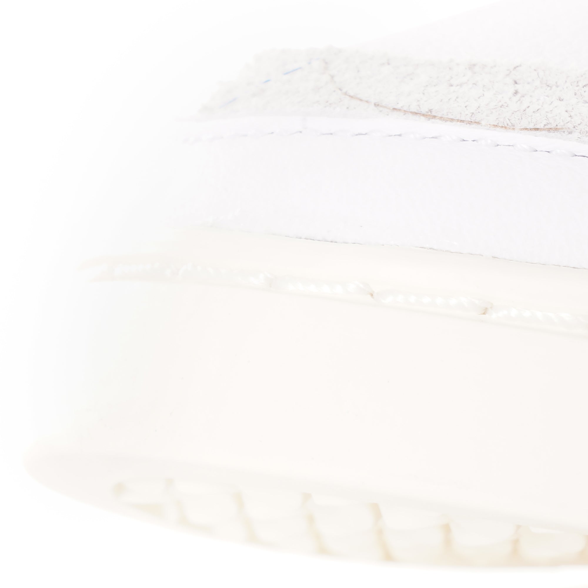 A close-up of the textured cream sole and white upper of an adidas Supercourt sneaker.