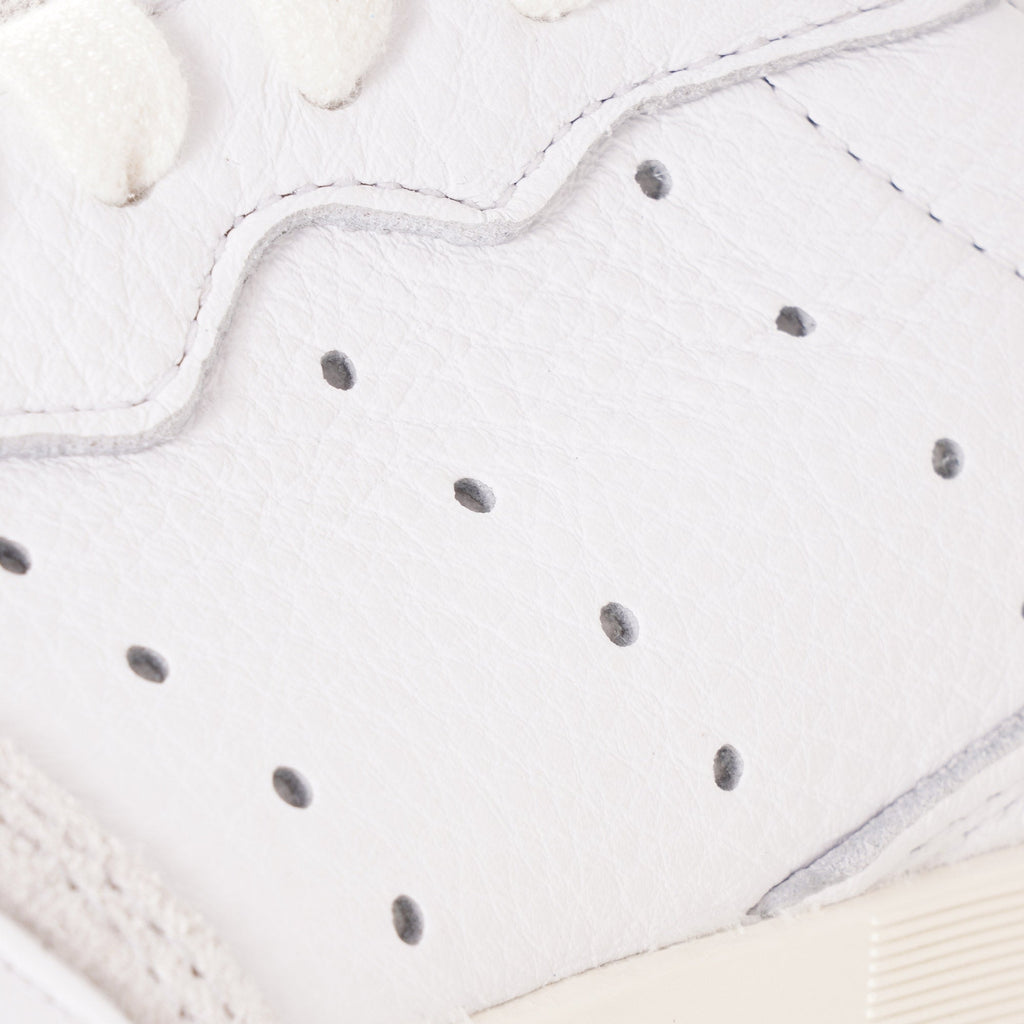 A close-up of the perforated detail on the side of a white adidas Supercourt sneaker.