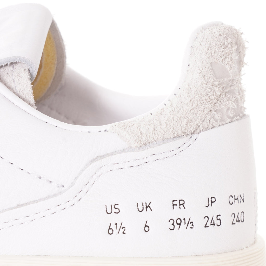 A close-up of the size conversions on the side of a white adidas Supercourt sneaker.