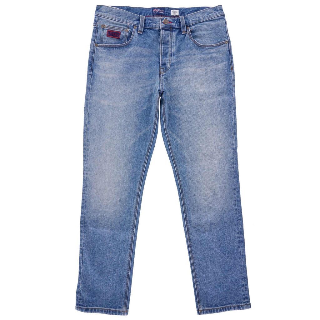 Front view of light blue denim jeans with a red logo patch on the right pocket.