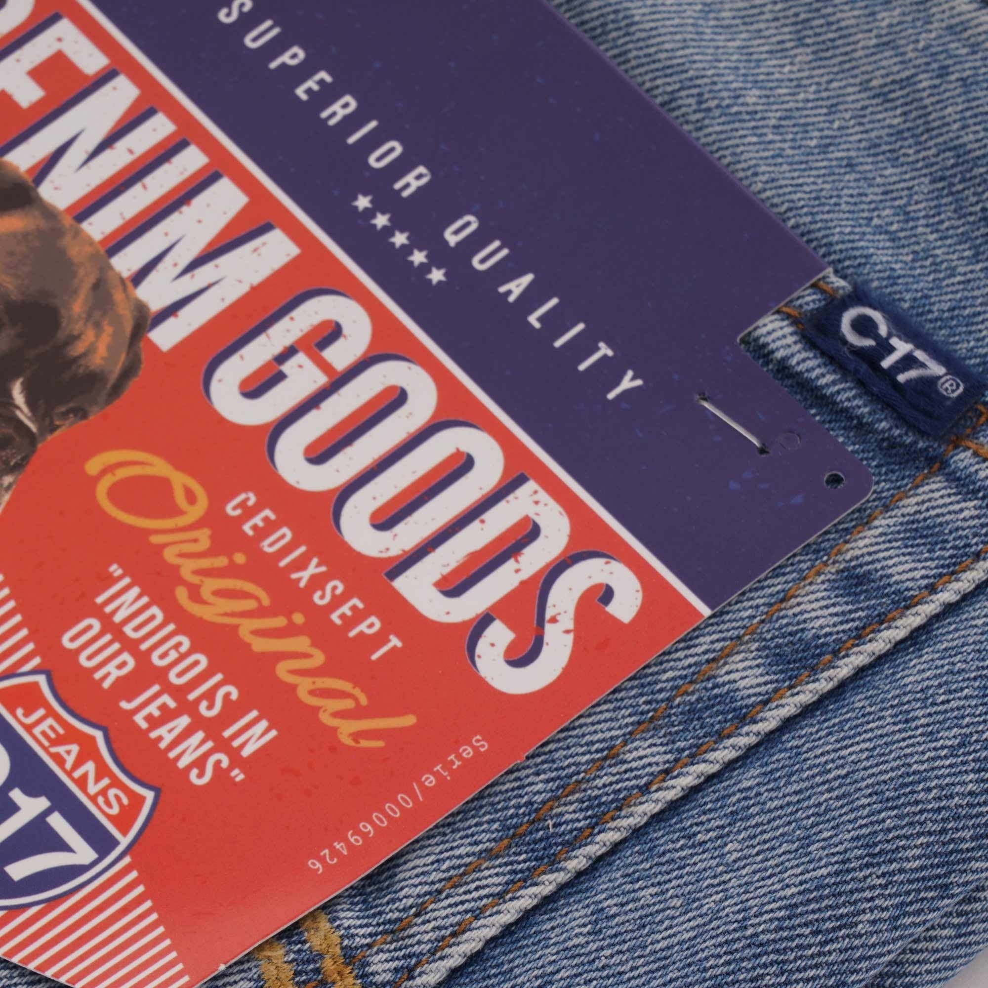 Close-up of the brand tag on blue denim jeans, highlighting 'DENIM GOODS'.