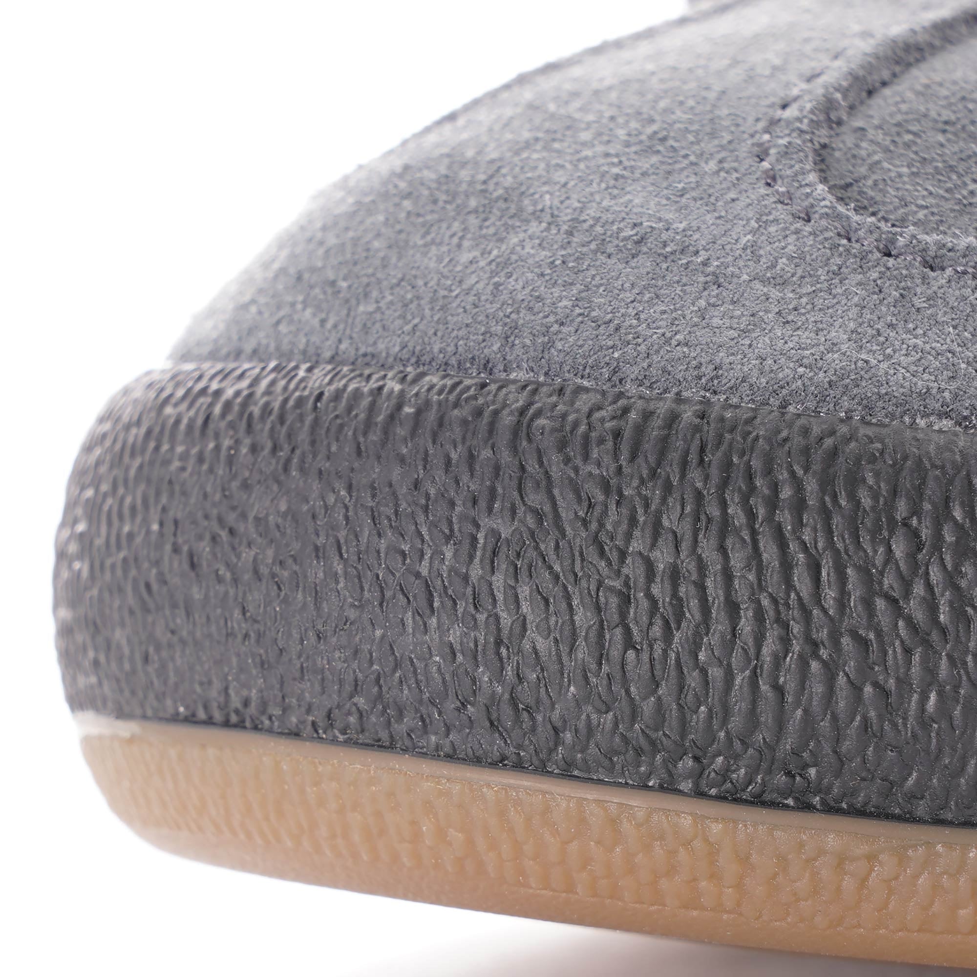 A close-up of the textured toe cap of a grey Adidas Jeans trainer.