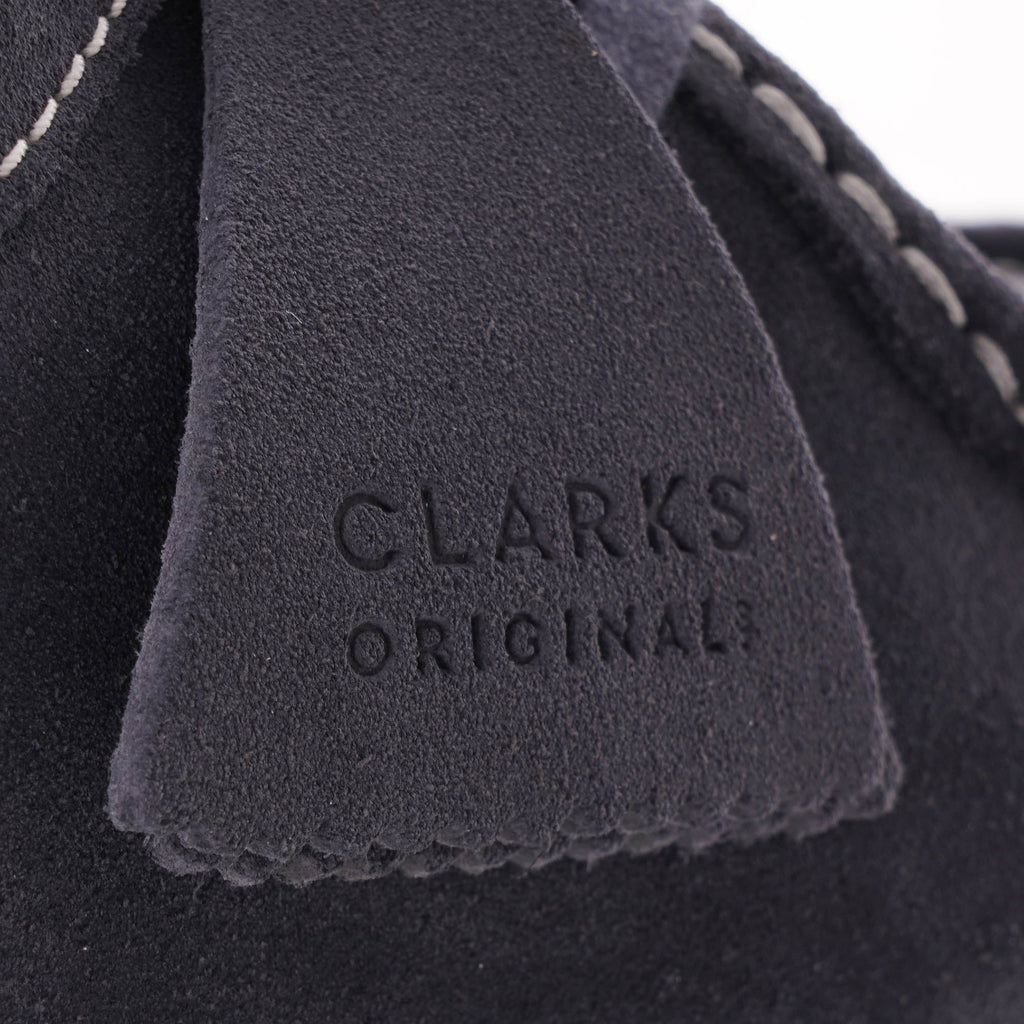 Close-up of the dark blue suede tag on the shoe with 'CLARKS ORIGINAL' embossed.
