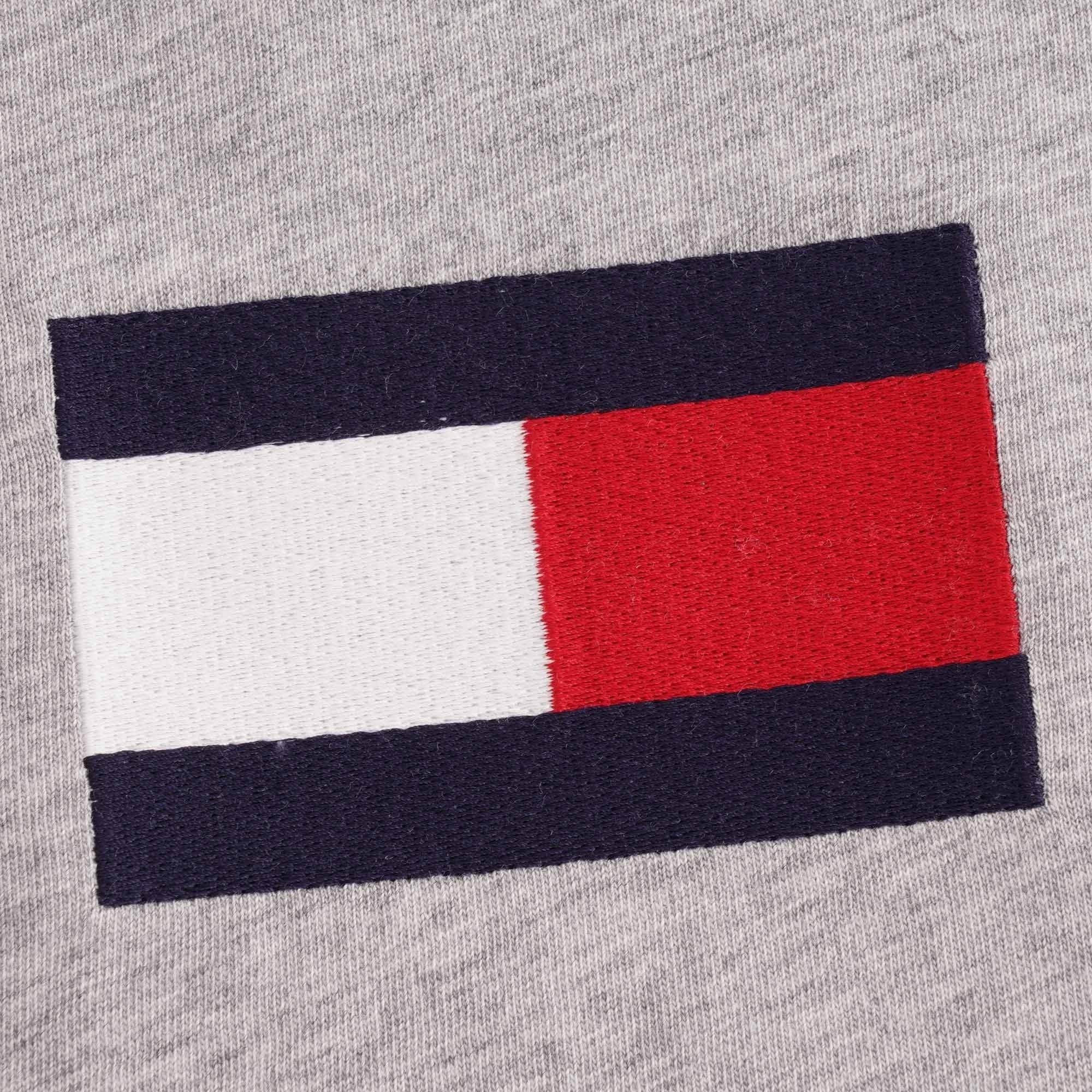 A detailed close-up of the Tommy Hilfiger flag logo on a grey t-shirt.