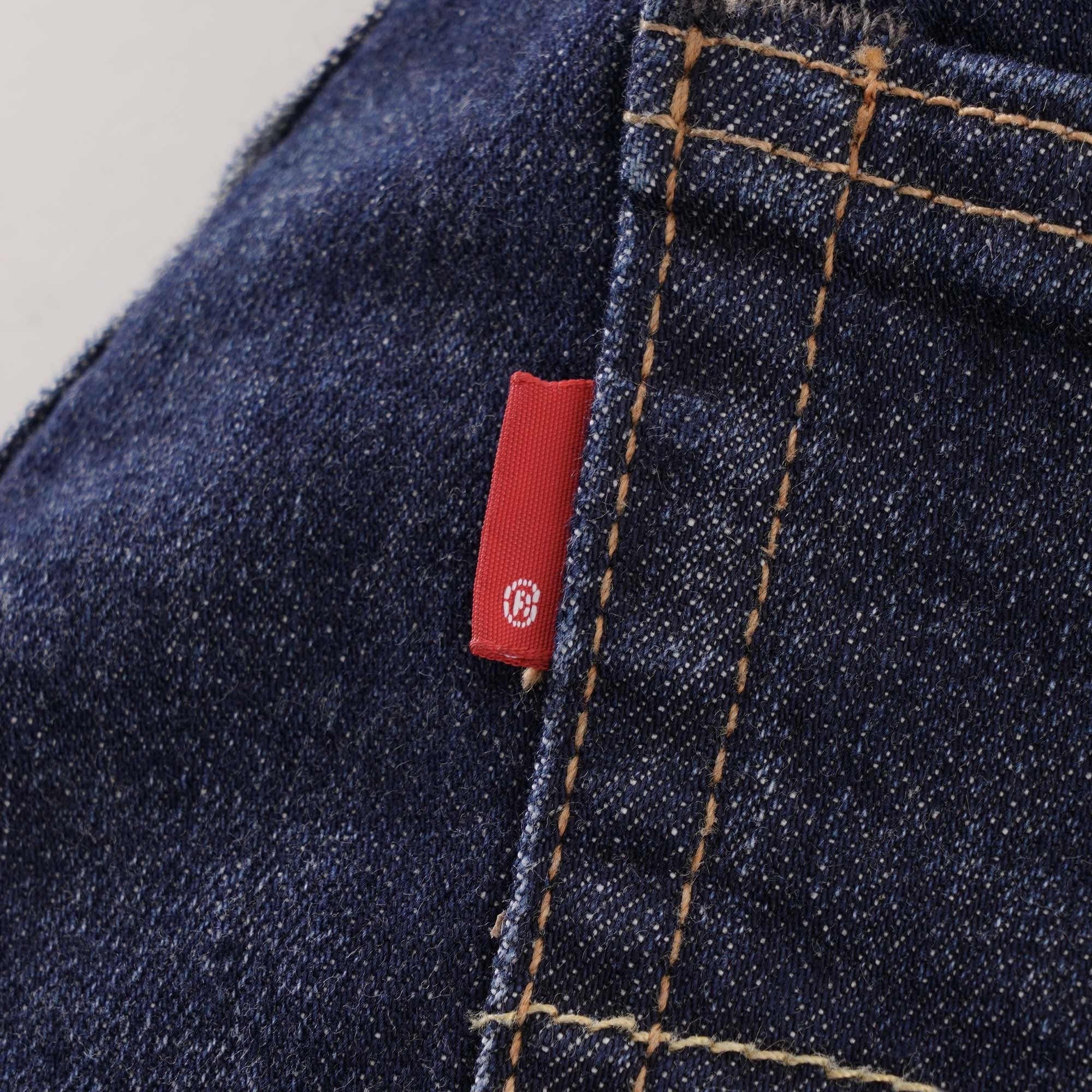 A close-up of the red Levi's tab on the back pocket of the dark wash jeans.