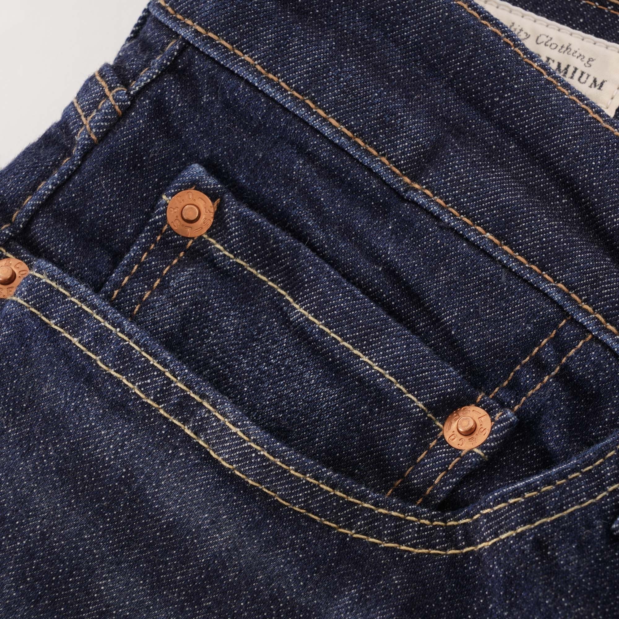 A close-up of the front pocket and copper rivets on the dark wash Levi's jeans.