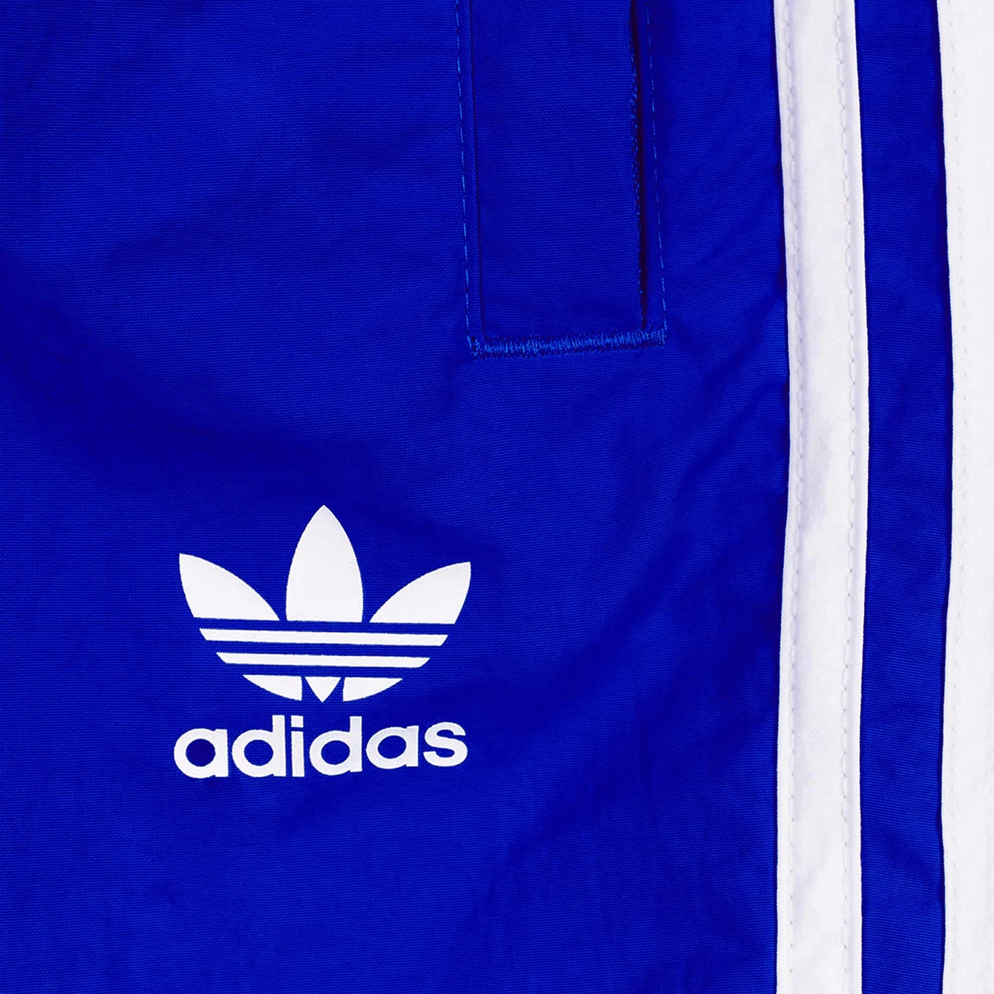 Close-up of the white Adidas Trefoil logo on the blue shorts.
