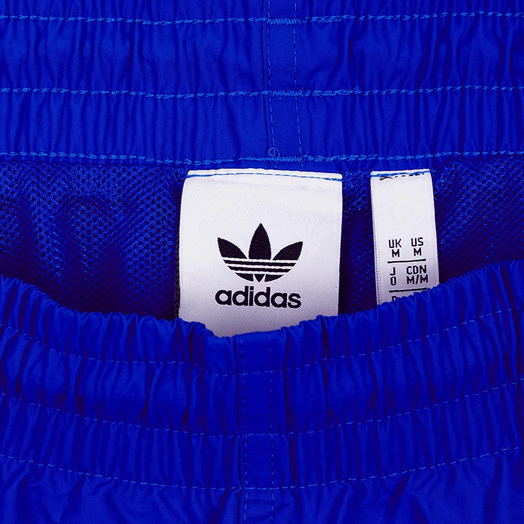 Close-up of the Adidas label and size tag inside the blue shorts.