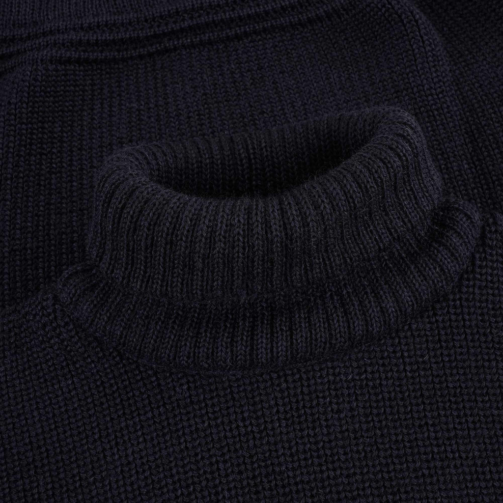 Close-up of the ribbed roll neck of a navy blue jumper.