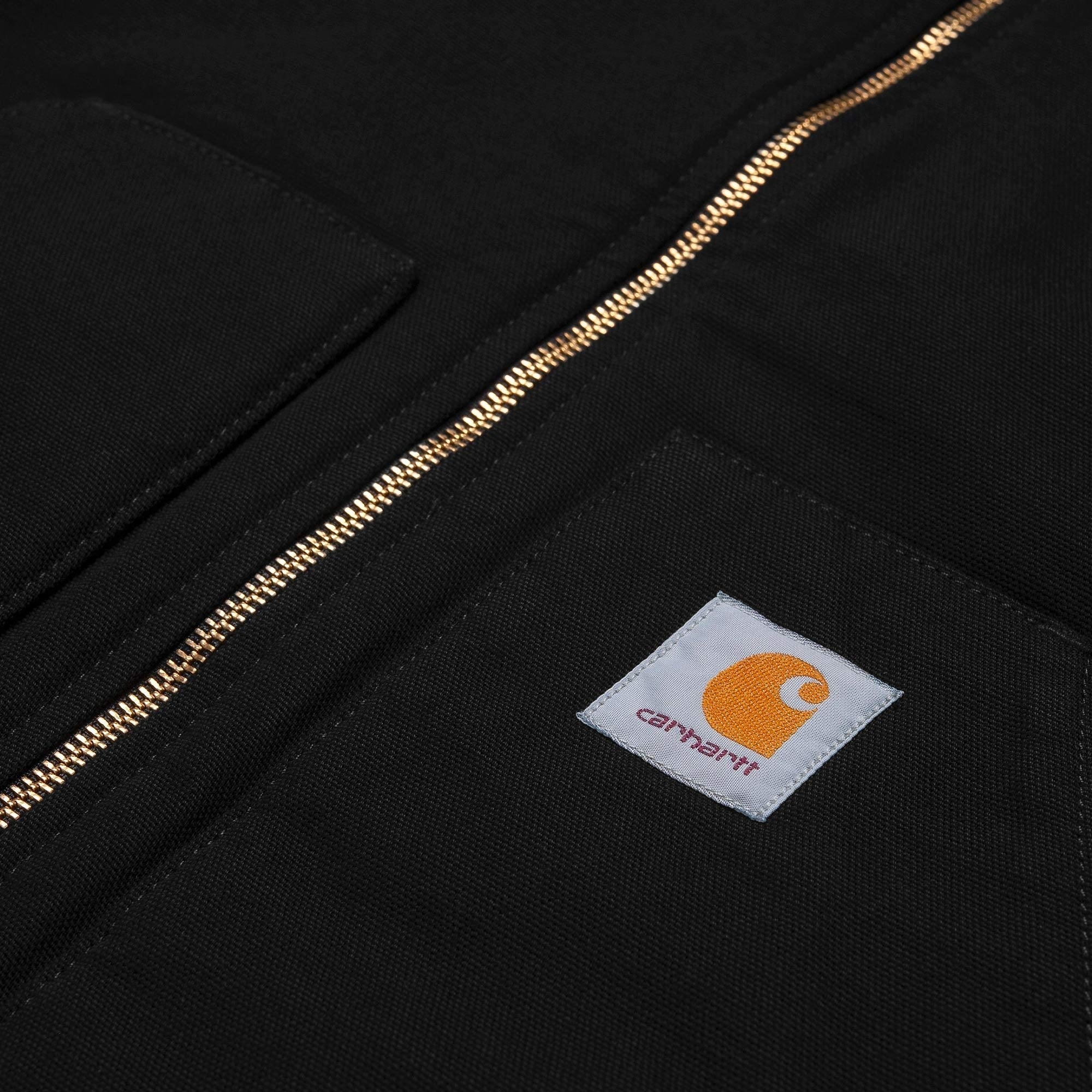 Close-up of the black Carhartt WIP vest, showing the gold zip and brand logo on the pocket.
